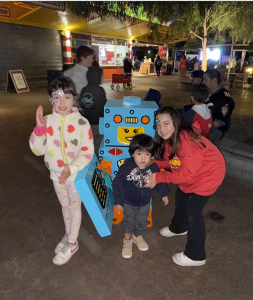 Three children standing by a life-size robot made out of Legos at Legoland at night.